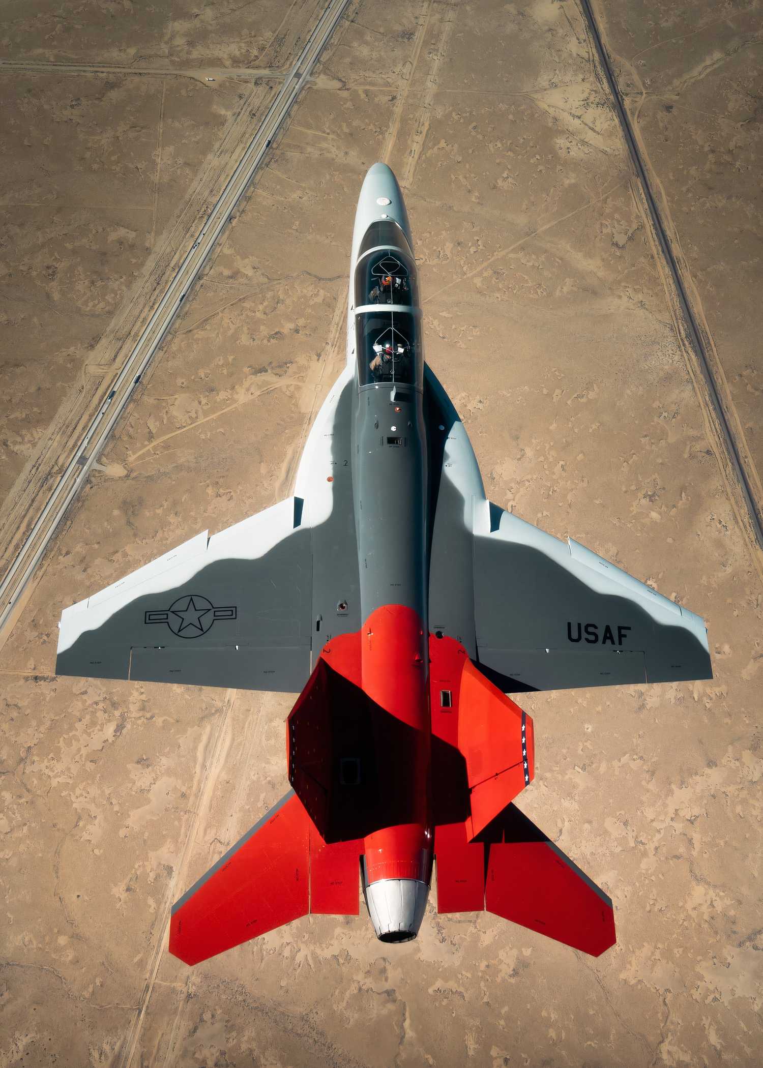 A Photo of a T-7 Red Hawk flying over a desert.