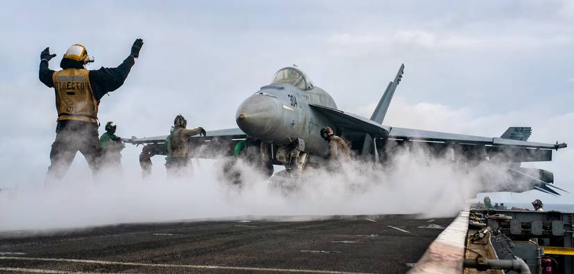 A photo of an F/A-18 Super Hornet preparing to takeoff aboard an aircraft carrier.
