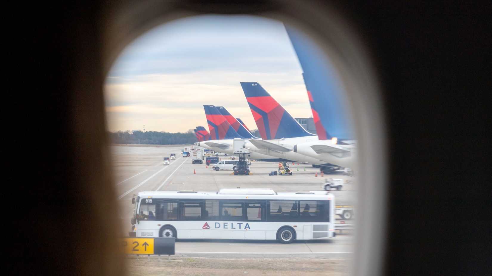 View through an airplane window of multiple Delta Air Lines aircraft parked at gates at Hartsfield-Jackson Atlanta International Airport. 