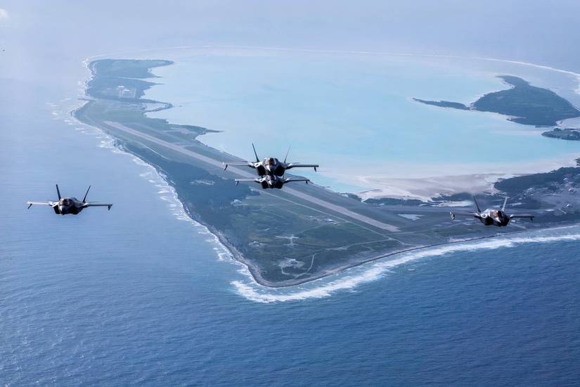 Four F-35s fly in tight formation with Wake Island in the immediate background. 