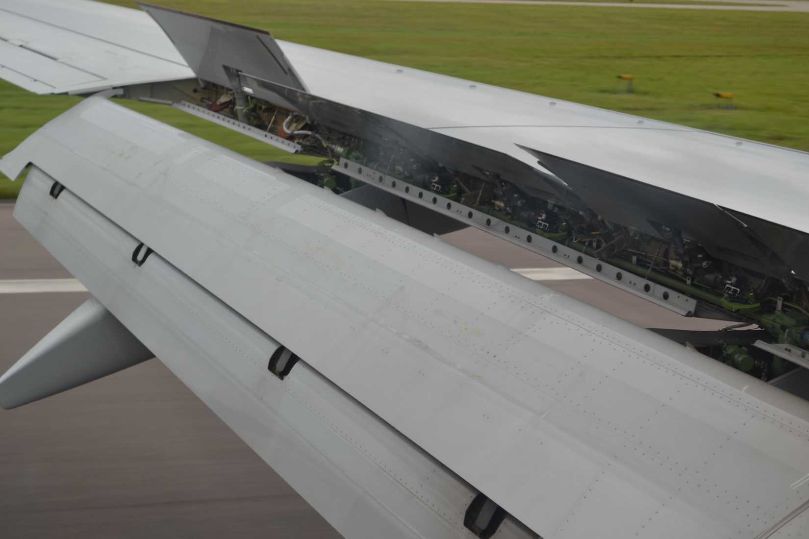 Aircraft wing from passenger window with flaps and spoilers deployed