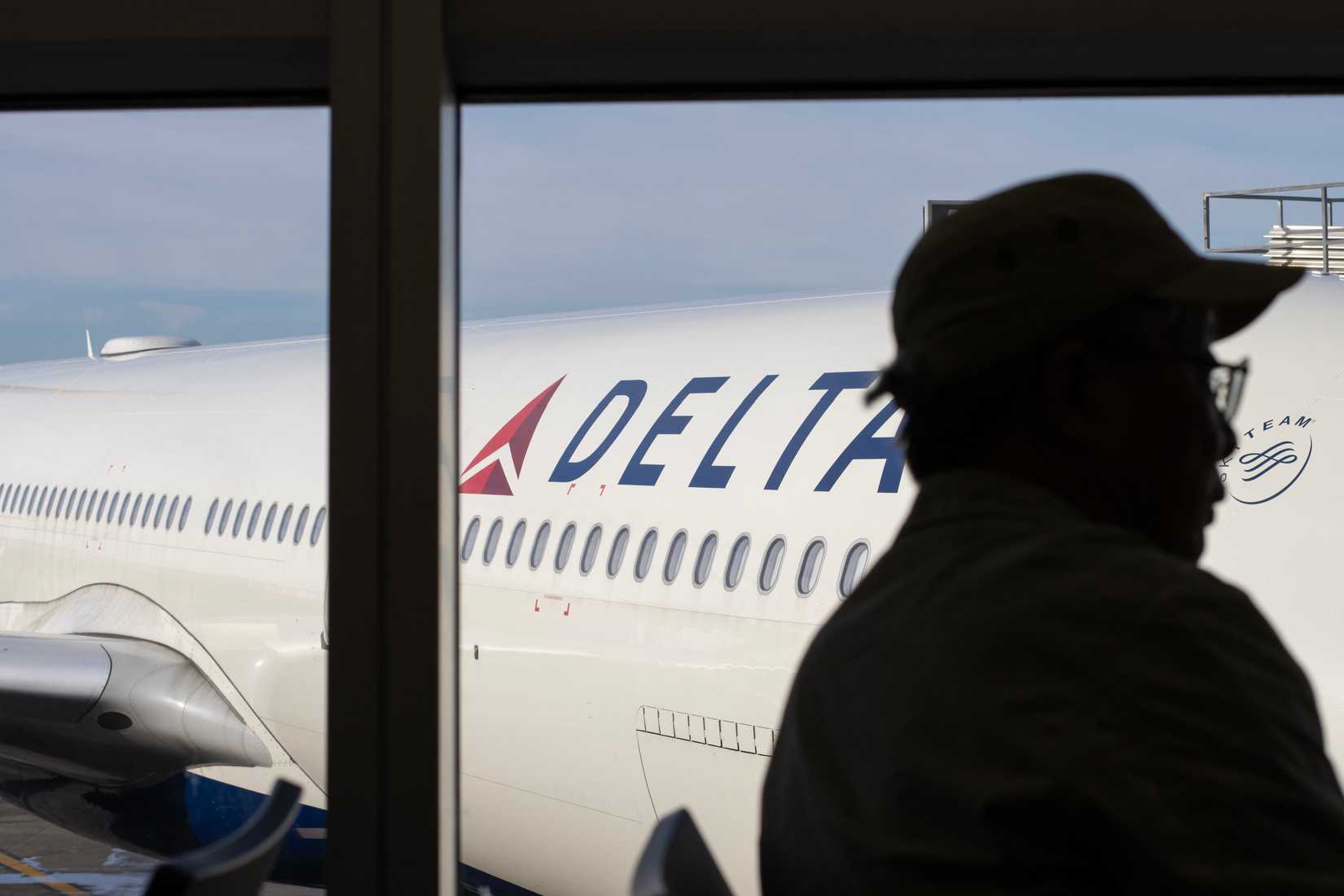 A Delta Air Lines jetliner is seen parked at a gate through the terminal lounge windows at Seattle-Tacoma International Airport.