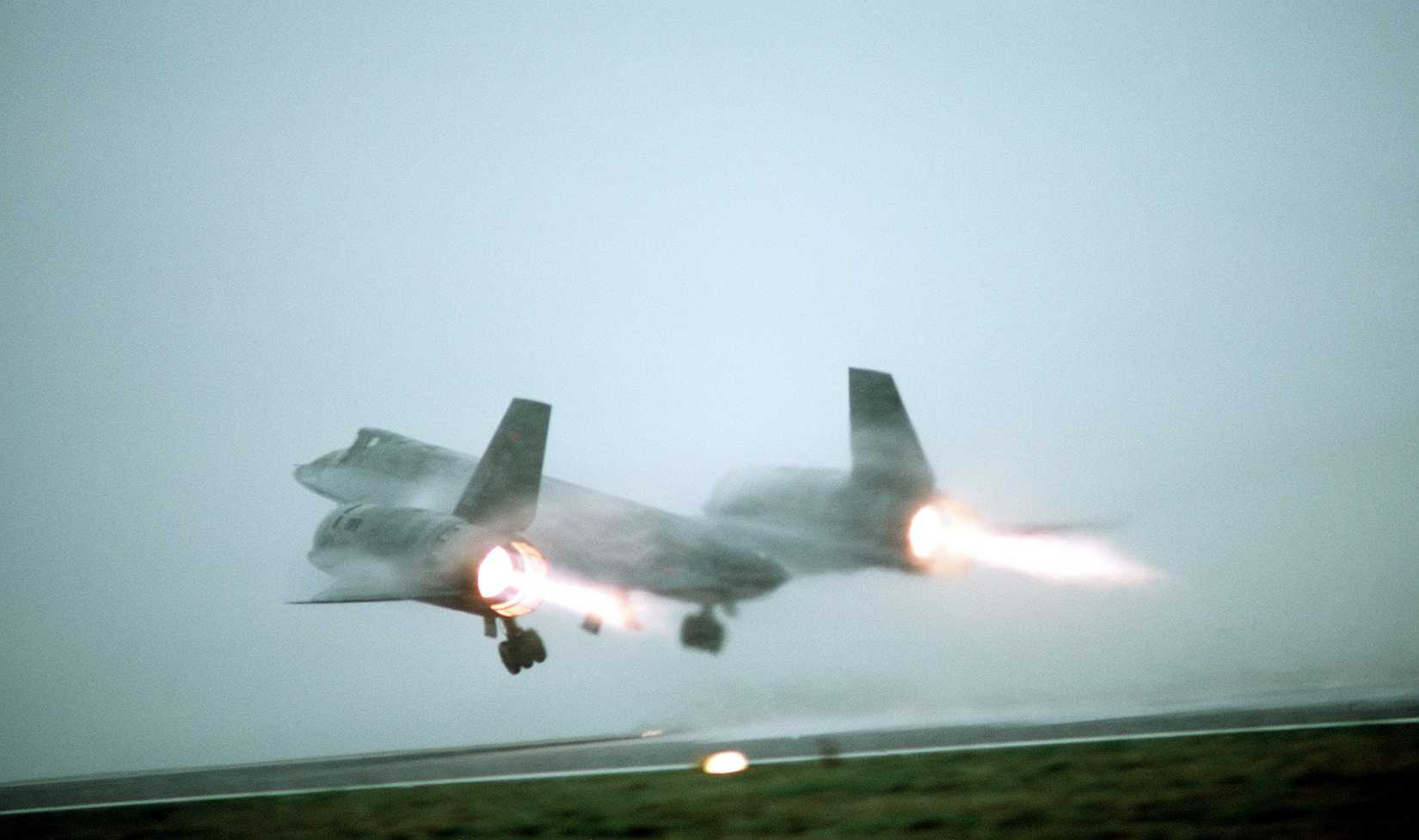 A ground-to-air left rear view of an SR-71 Blackbird aircraft taking off from a fog-shrouded runway. The SR-71 is flown by Det. 4, 9th Strategic Reconnaissance Wing, 3rd Air Force, RAF Mildenhall