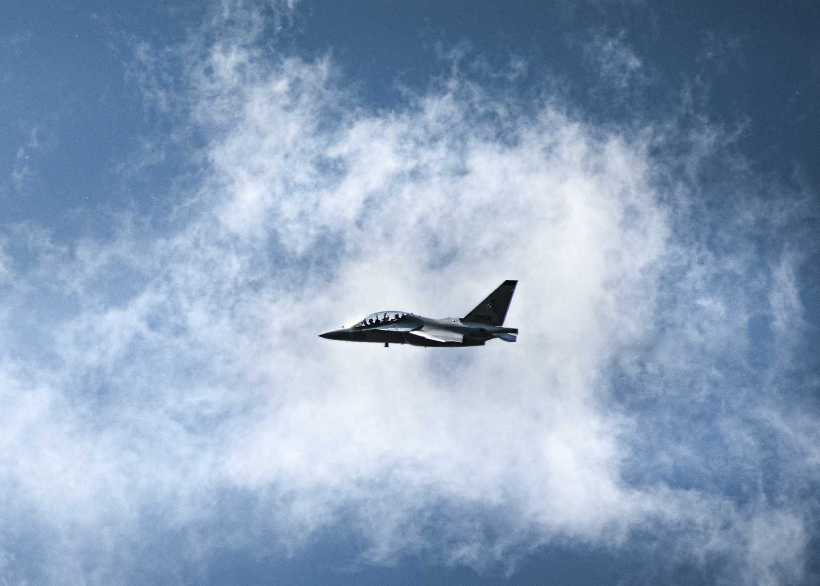 A Polish air force Aermacchi M-346 Master jet trainer flies over a wet-gap crossing operation part of Defender Europe 22 held at Dęblin, Poland