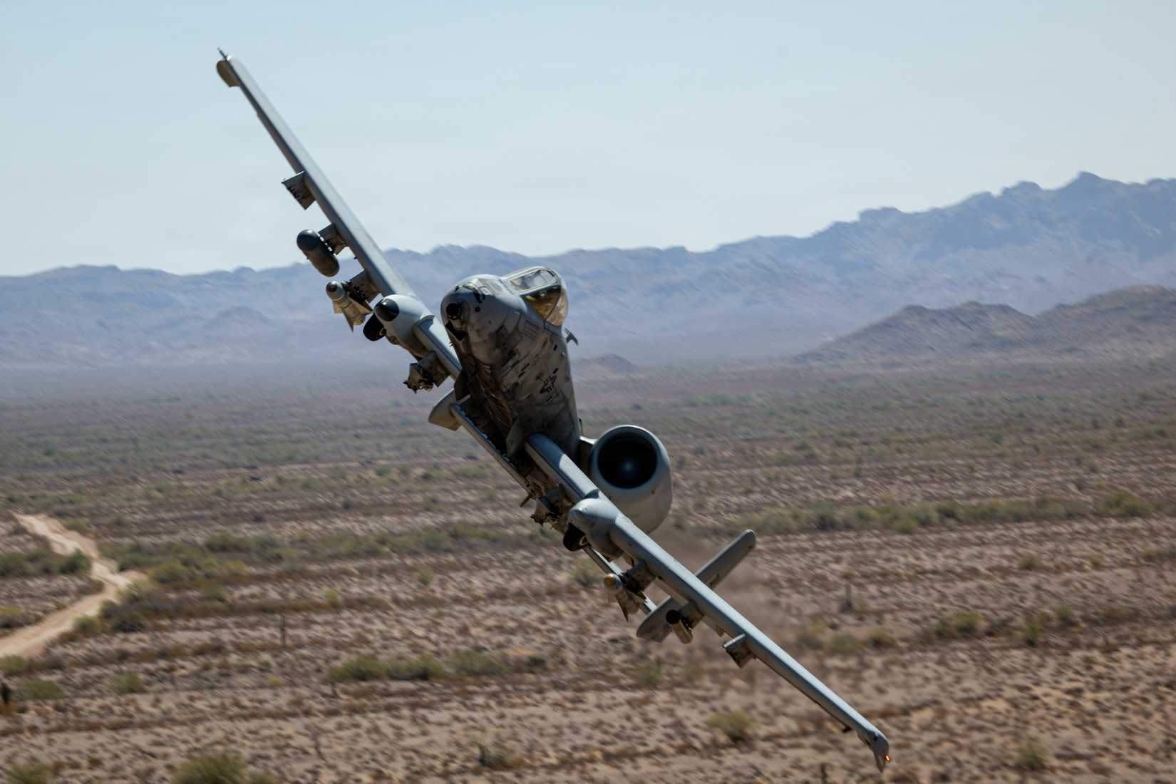 A U.S. Air Force Fairchild Republic A-10 Thunderbolt II assigned to the 357th Fighter Squadron, 355th Fighter Wing, flies over a training site