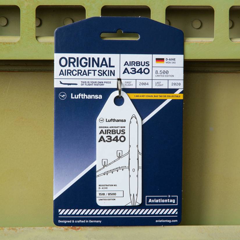 A retail-packaged white Aviationtag made from the original aircraft skin of a Lufthansa Airbus A340, with the registration number D-AIHE. The tag displays an outline graphic of the four-engine aircraft and its limited-edition series number (1518 / 8500), mounted on its original blue and white cardboard backing displaying the aircraft's operational history (First Flight 2004, Last Flight 2020).