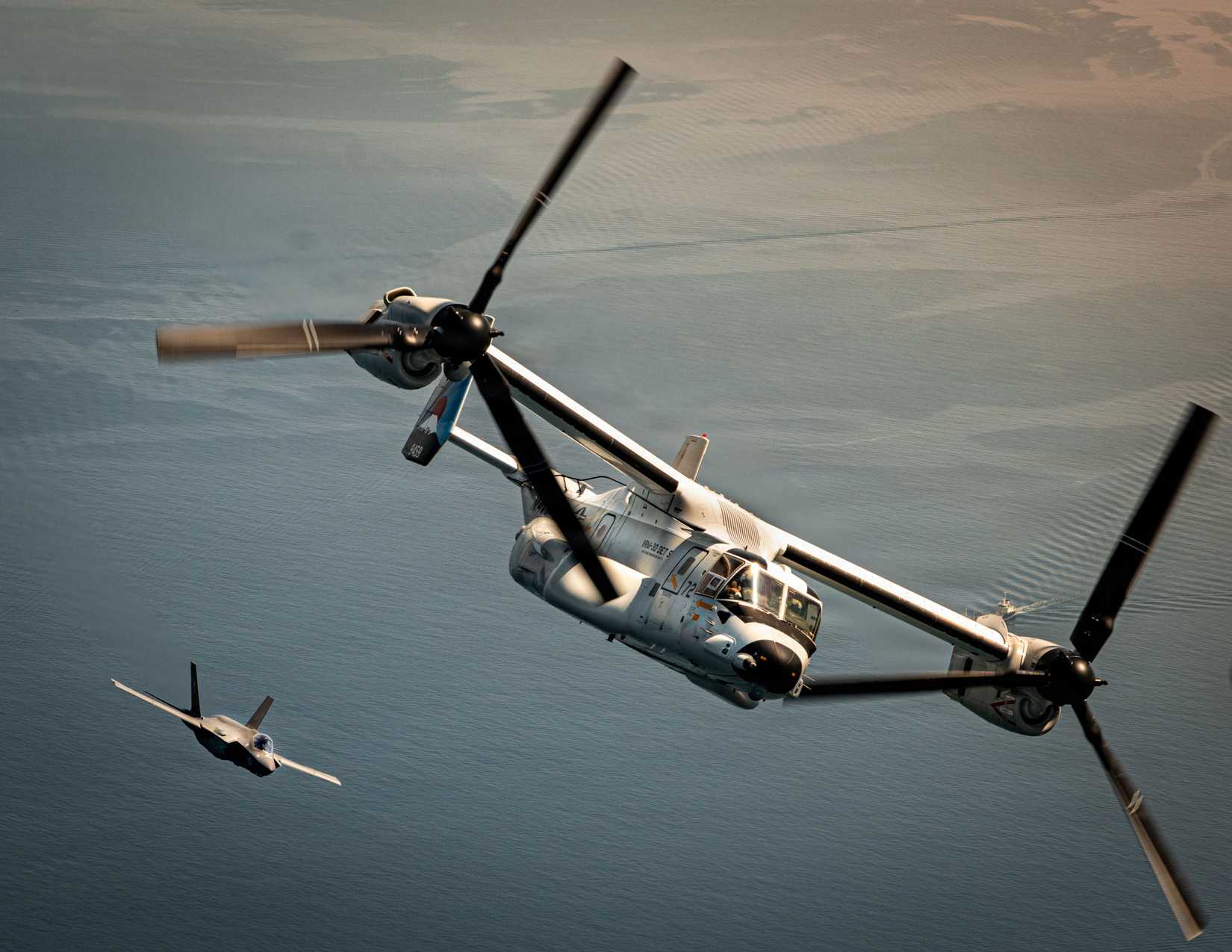 An F-35C Lightning II aircraft with Strike Fighter Squadron (VFA) 147 trails a CMV-22B Osprey with Fleet Logistics Multi-Mission Squadron (VRM) 30