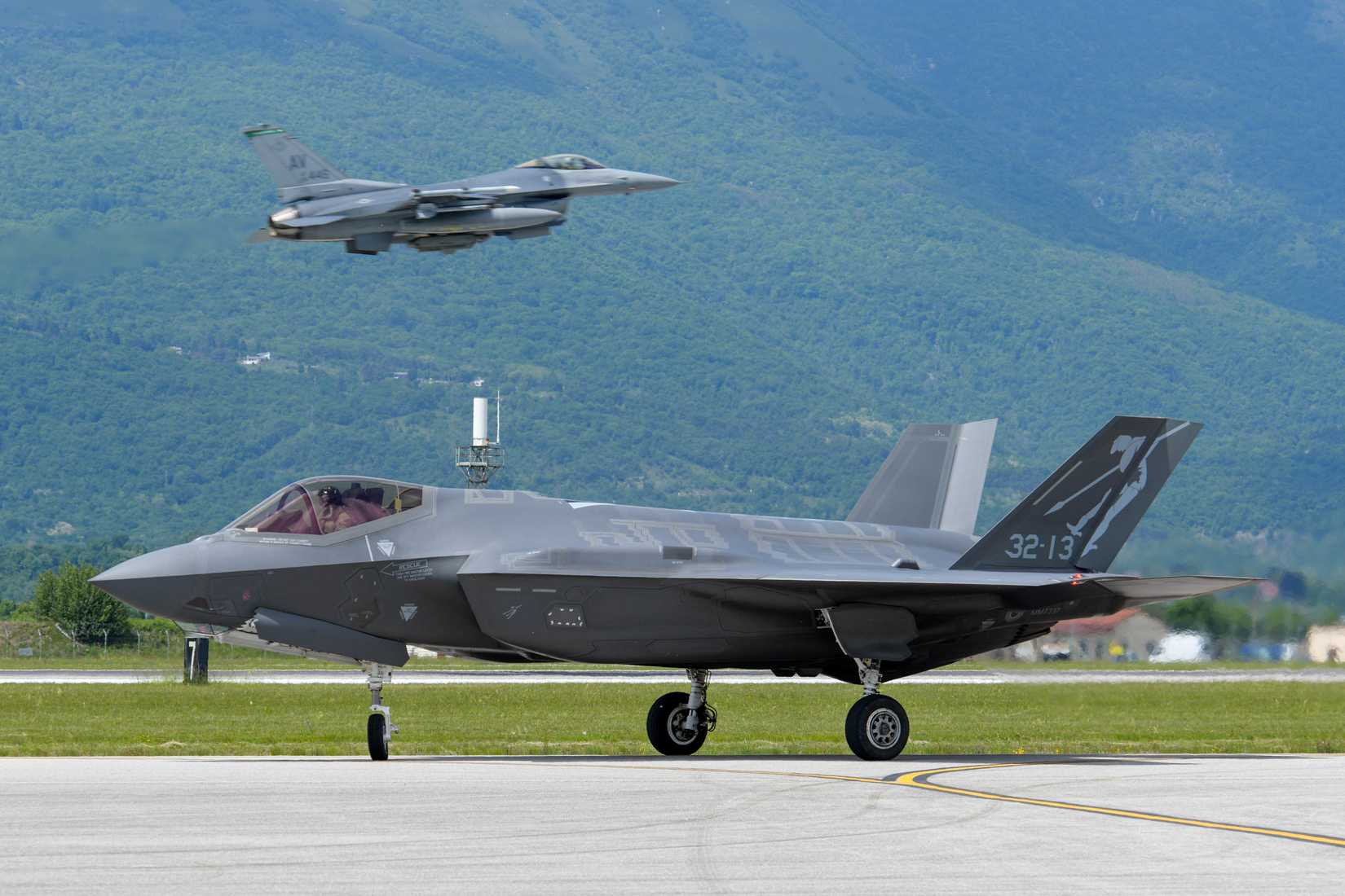 An Italian air force F-35A Lightning II assigned to the 32nd Wing, Amendola Air Base, Italy, taxis while a U.S. Air Force F-16 Fighting Falcon takes off