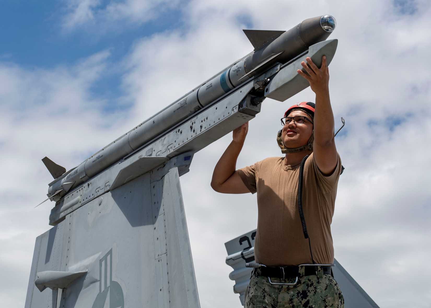 Aviation Ordnanceman 3rd Class Christian Delacruz secures an Air Intercept Missile-9X (AIM-9X) to an F?A-18F Super Hornet
