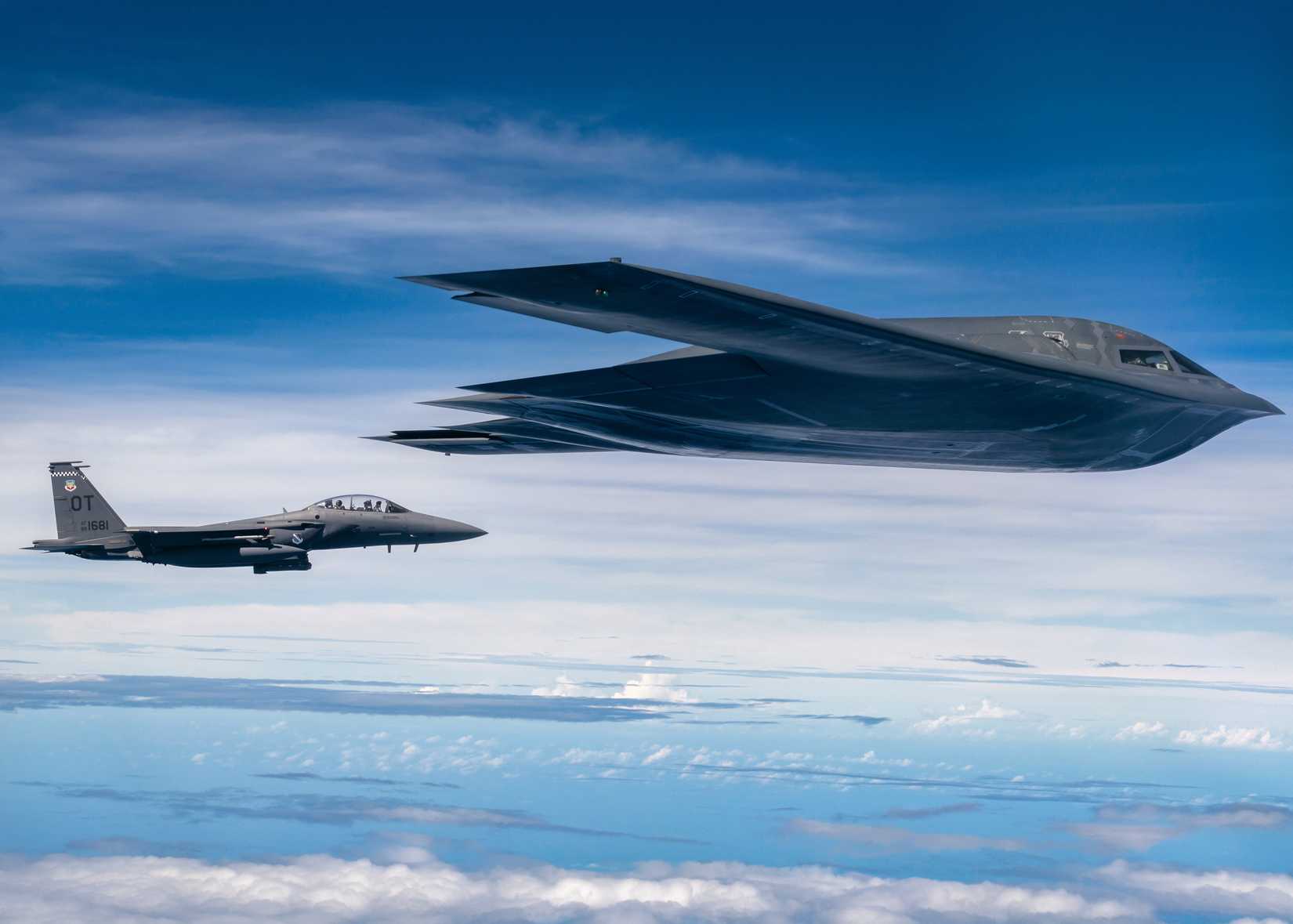 A photo of a B-2 flying in tandem with a F-15 somewhere above the Pacific