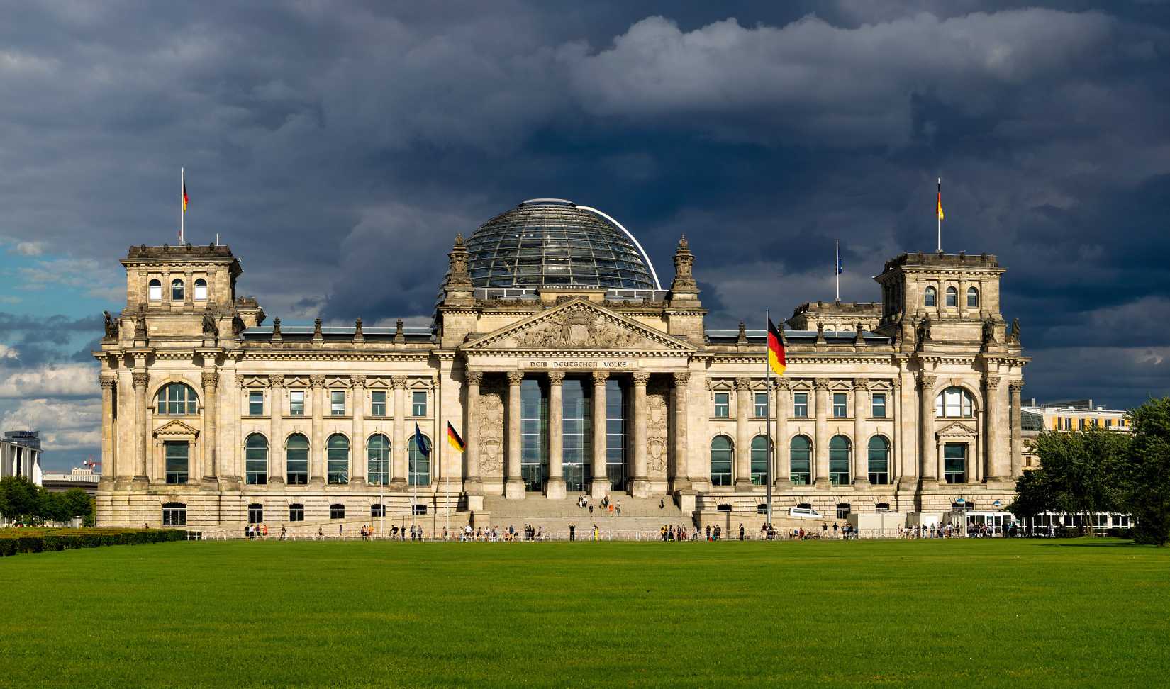 A photo of the German Bundestag, with dark clouds in the background. 