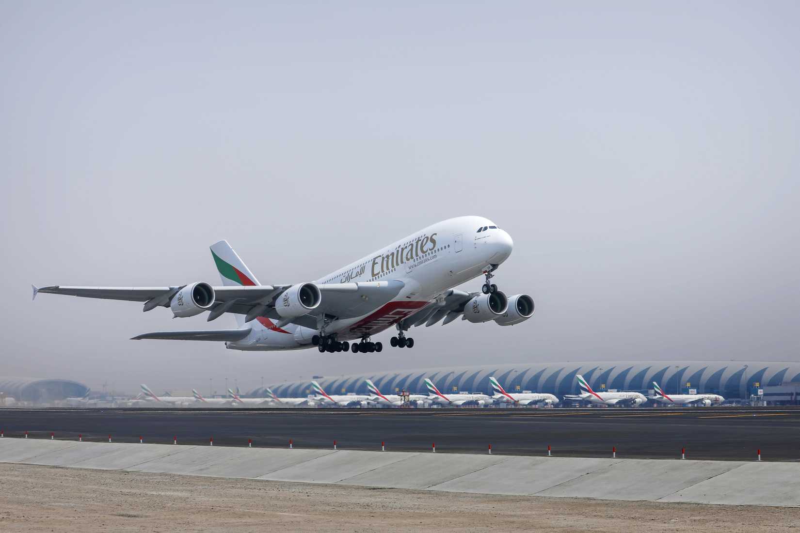 Emirates A380 Taking Off In Dubai With Other A380s Parked At The Terminal