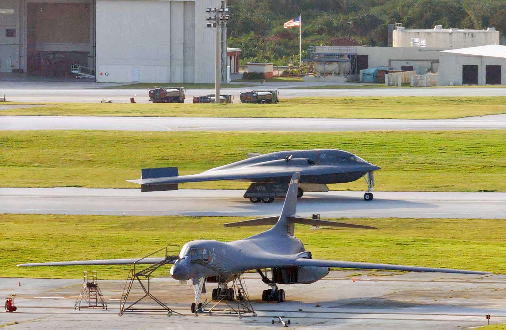 A photo showing a B-1B Lancer parked in the foreground and a B-2 bomber taxiing immediately behind it..