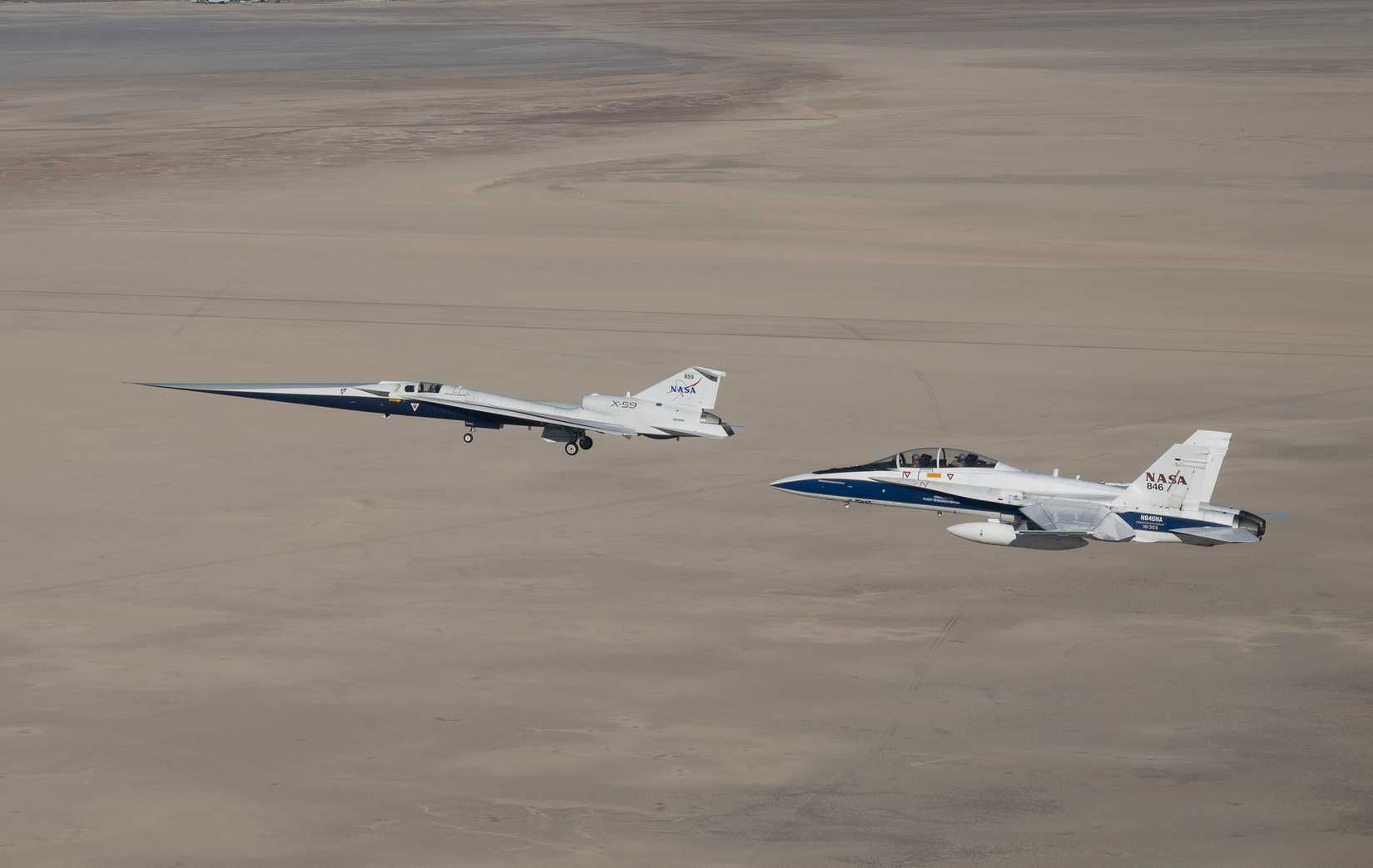 NASA’s X-59 quiet supersonic research aircraft flies above Palmdale and Edwards, California, during its first flight Tuesday, Oct. 28, 2025, accompanied by a NASA F⁄A-18 research aircraft.