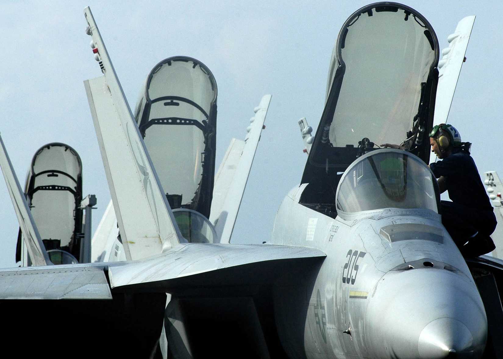 Navy Airman Jason Rickards adjusts some equipment in the cockpit of an FA-18E Super Hornet
