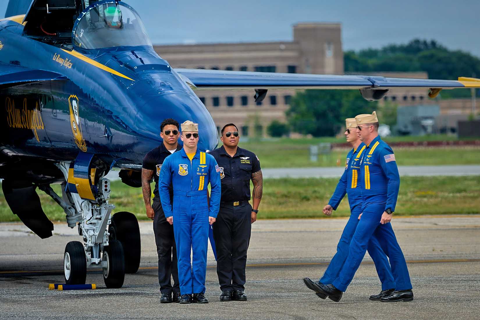 Navy Flight Demonstration Squadron, the Blue Angels, pilots and crew members walk across the flight line after a flight demonstration during SAIL250