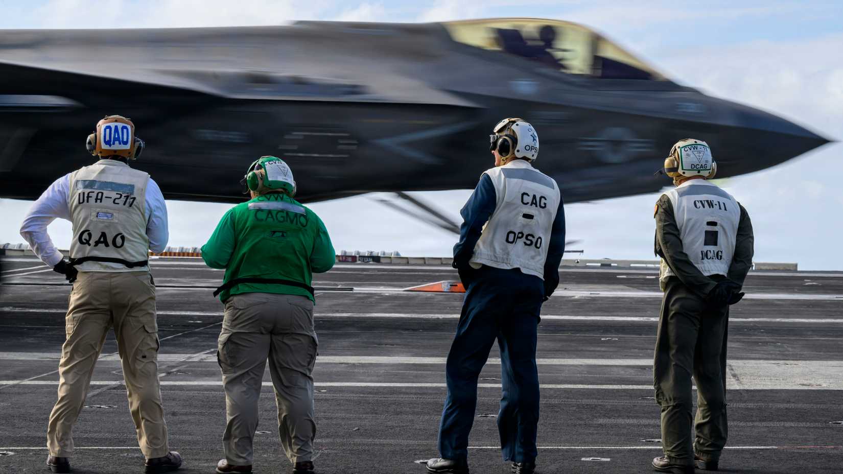 Navy Sailors observe the landing of an F-35C Lightning II assigned to Strike Fighter Squadron (VFA) 86 on the flight deck of Nimitz-class aircraft carrier USS Theodore Roosevelt (CVN 71)