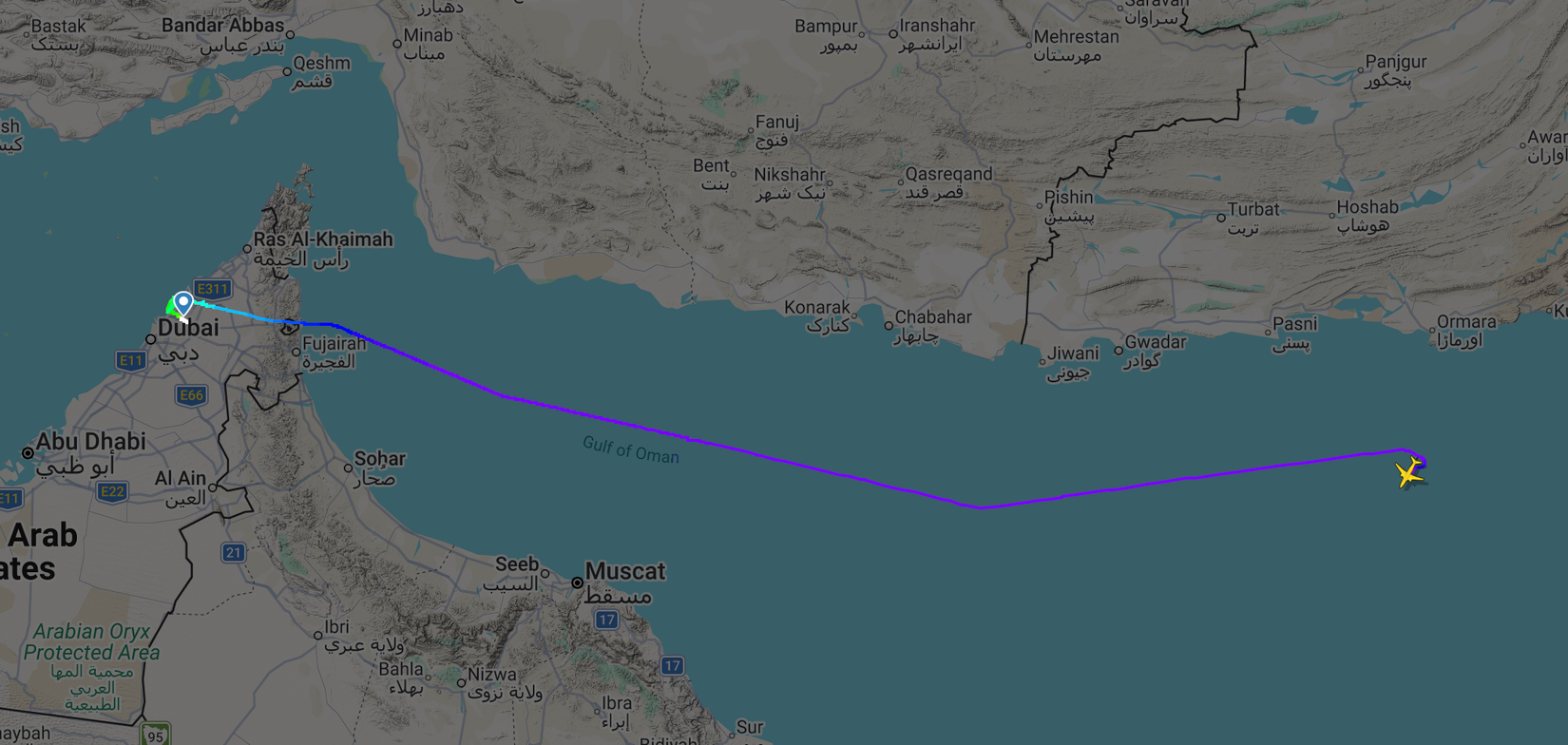 A flight tracking map screenshot showing a yellow airplane icon traveling over the Gulf of Oman. The purple flight path line indicates the aircraft departed from Dubai, crossed over the eastern coast near Fujairah, and is heading east away from the United Arab Emirates and Oman toward Pakistan's coastline.