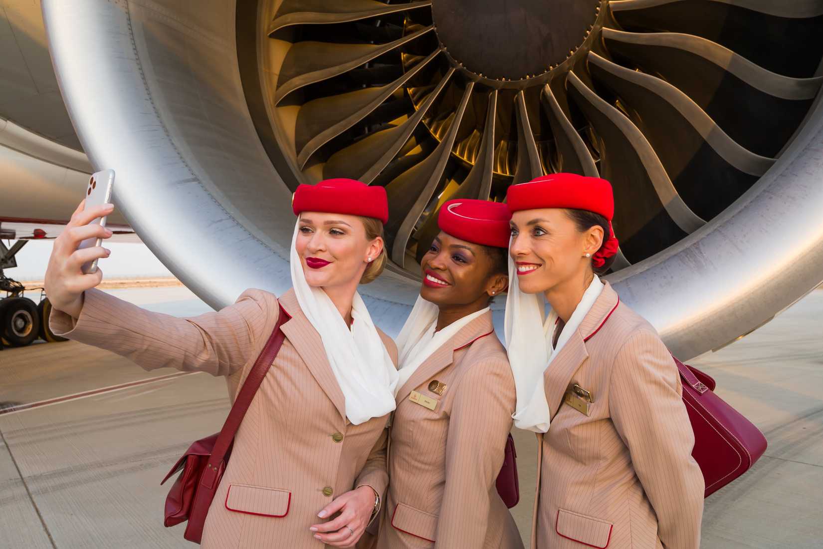 three emirates cabin crew standing next to engine