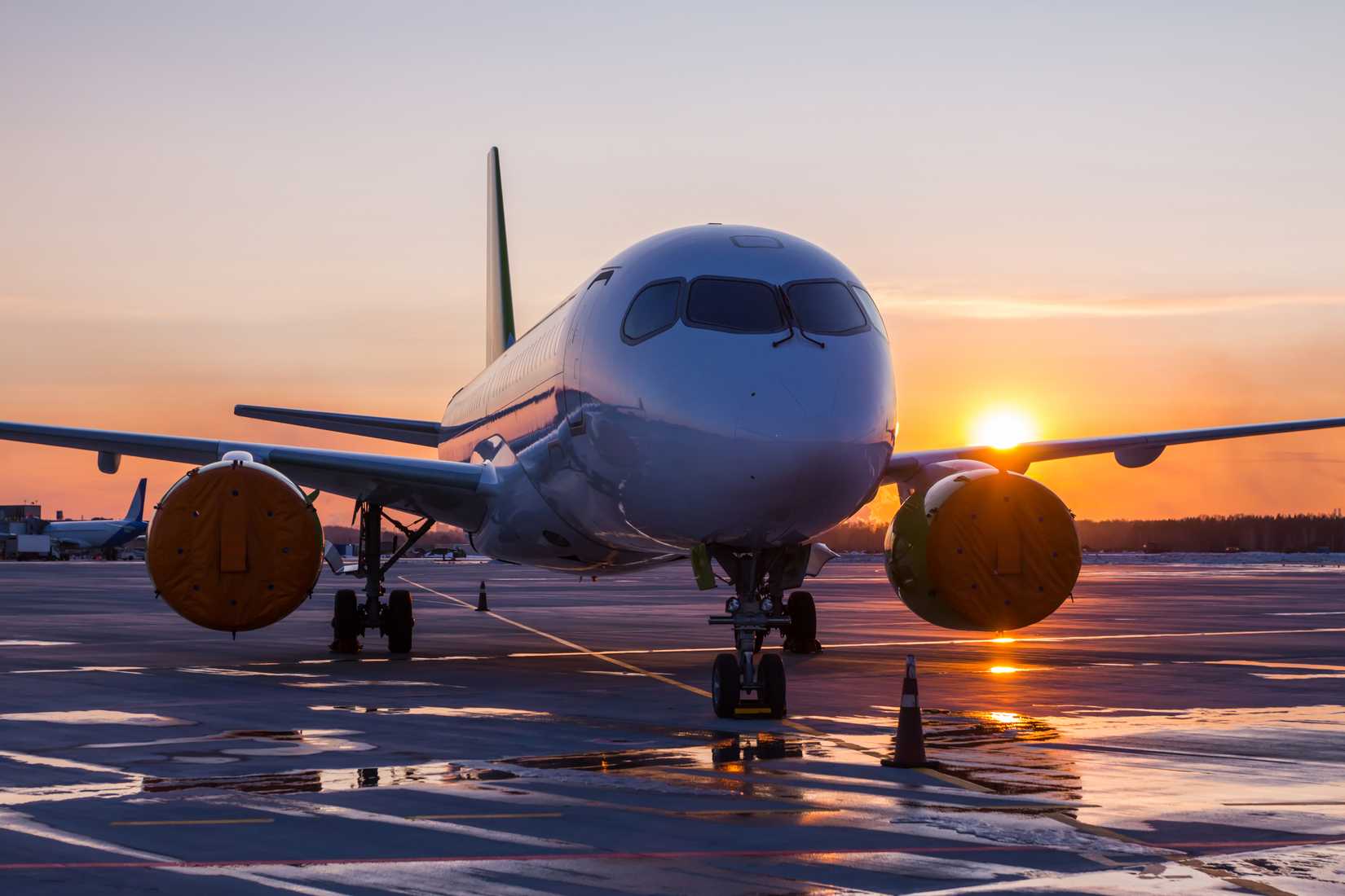 An aircraft on the airport apron against the backdrop of a sunset