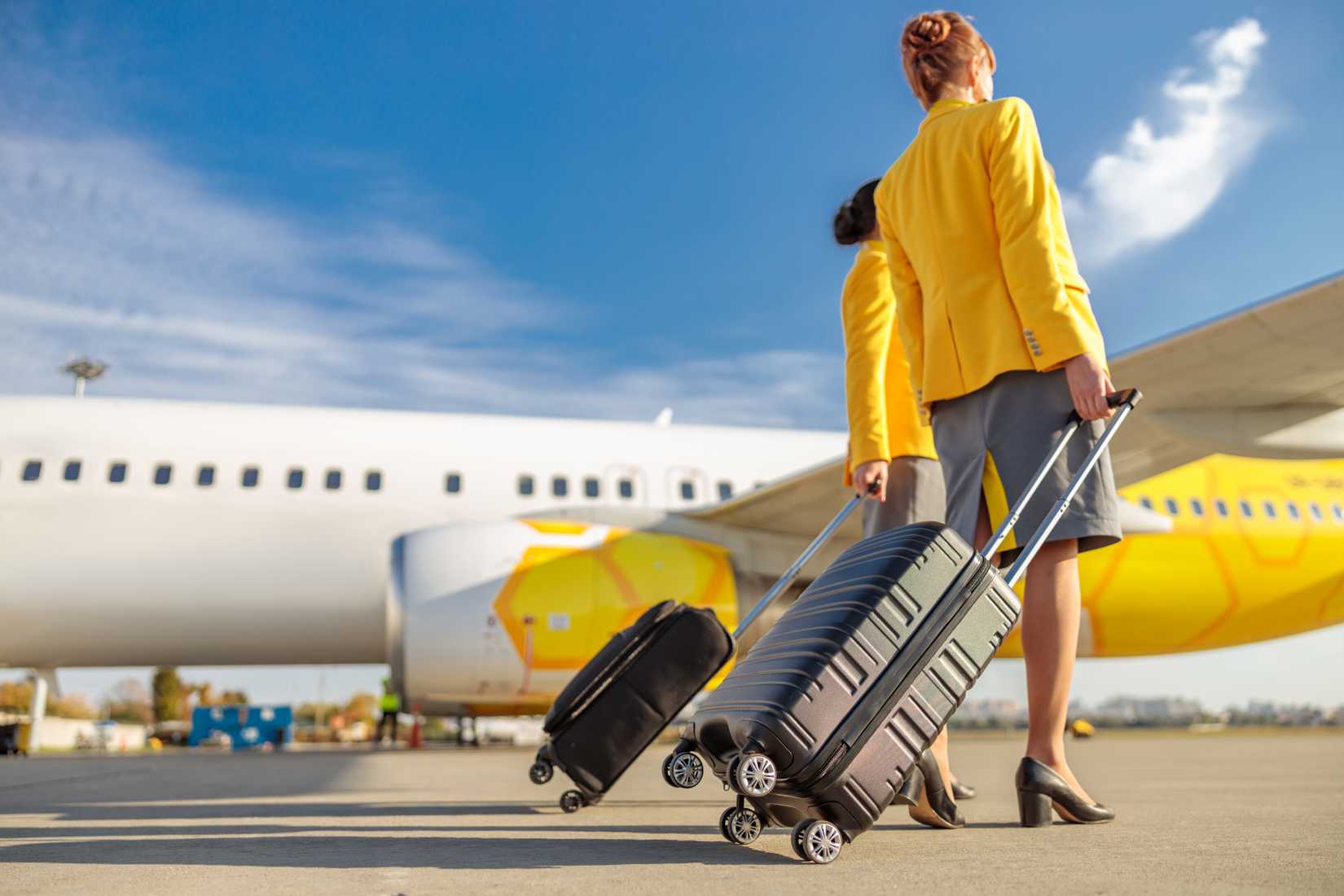 cabin crew with suitcases walking to the aircraft