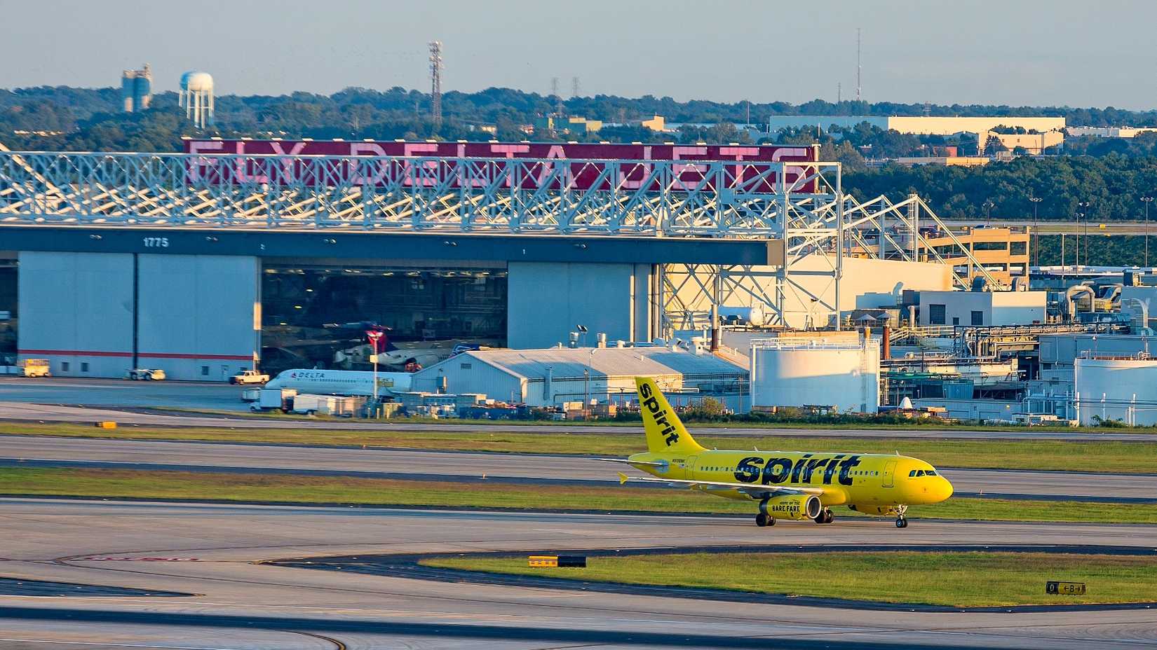 Spirit Airlines jet taxis past a Delta hangar in ATL