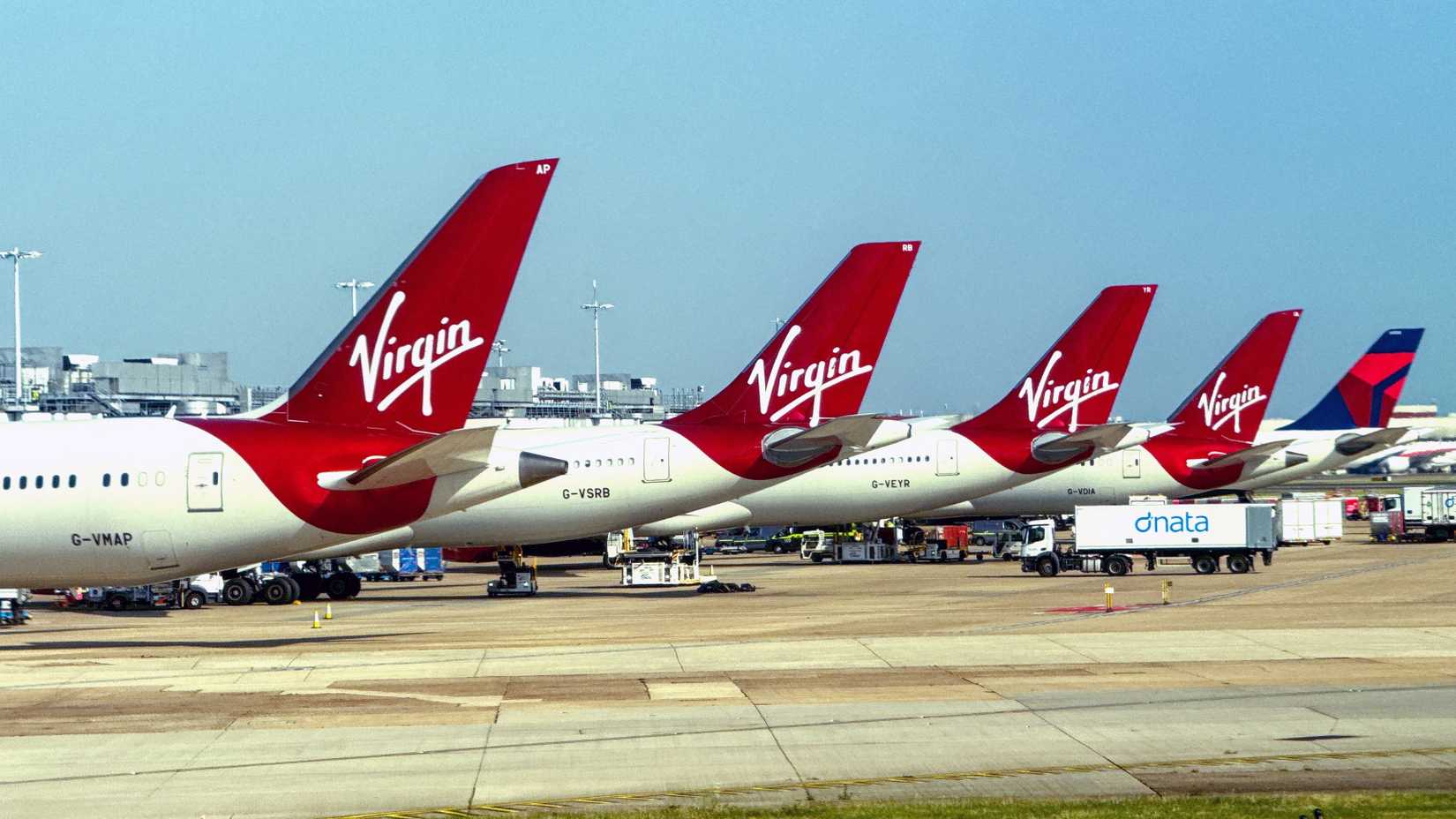 Tails fins of a row of Virgin Atlantic jets and a sole Delta Air Lines plane at London Heathrow airport%0A