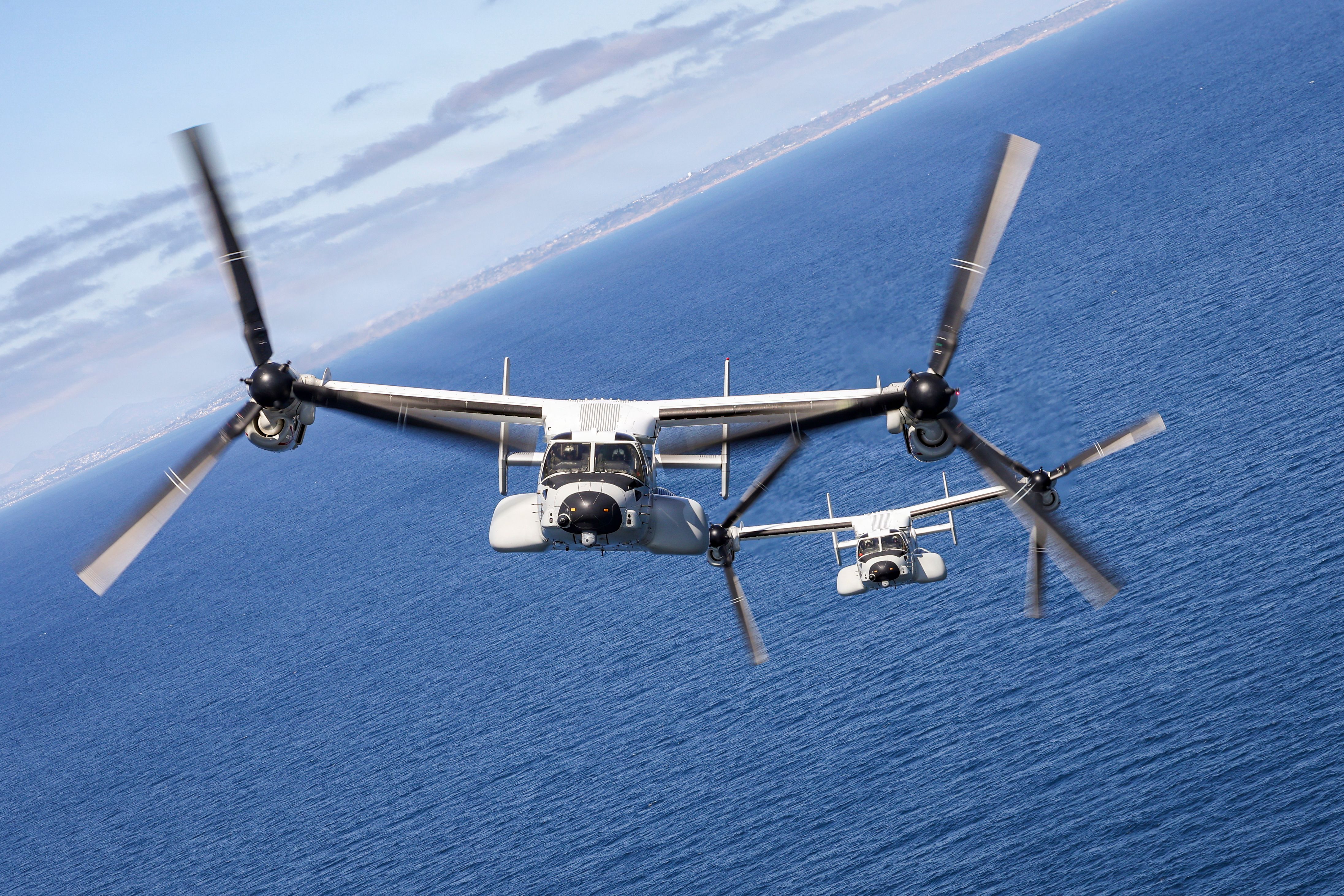Two U.S. Navy CMV-22B Osprey tiltrotor aircraft flying over the Pacific Ocean.
