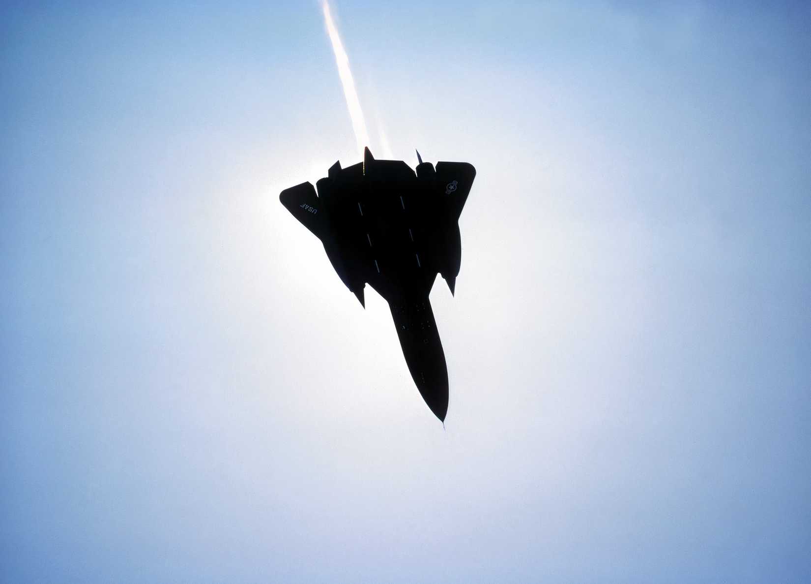 A photo of an SR-71 silhouetted against a blue sky