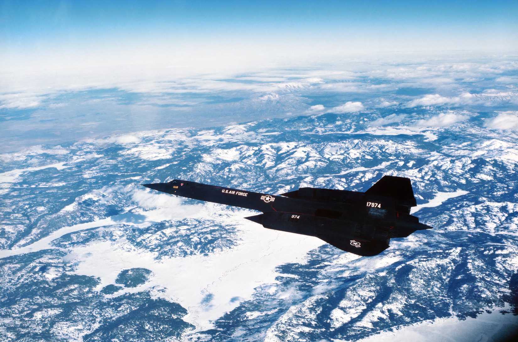 A photo of an SR-71 flying over a snowcapped mountain range.