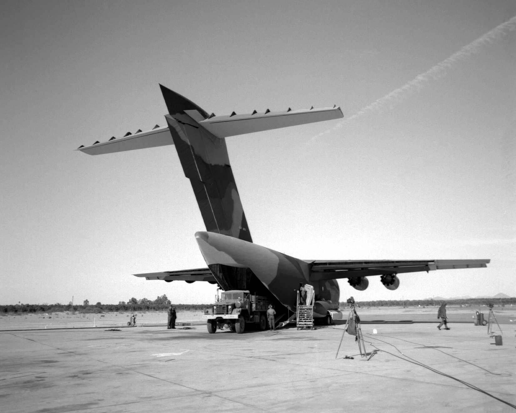 A cargo truck is offloaded from a YC-15 aircraft during a heavy loading test