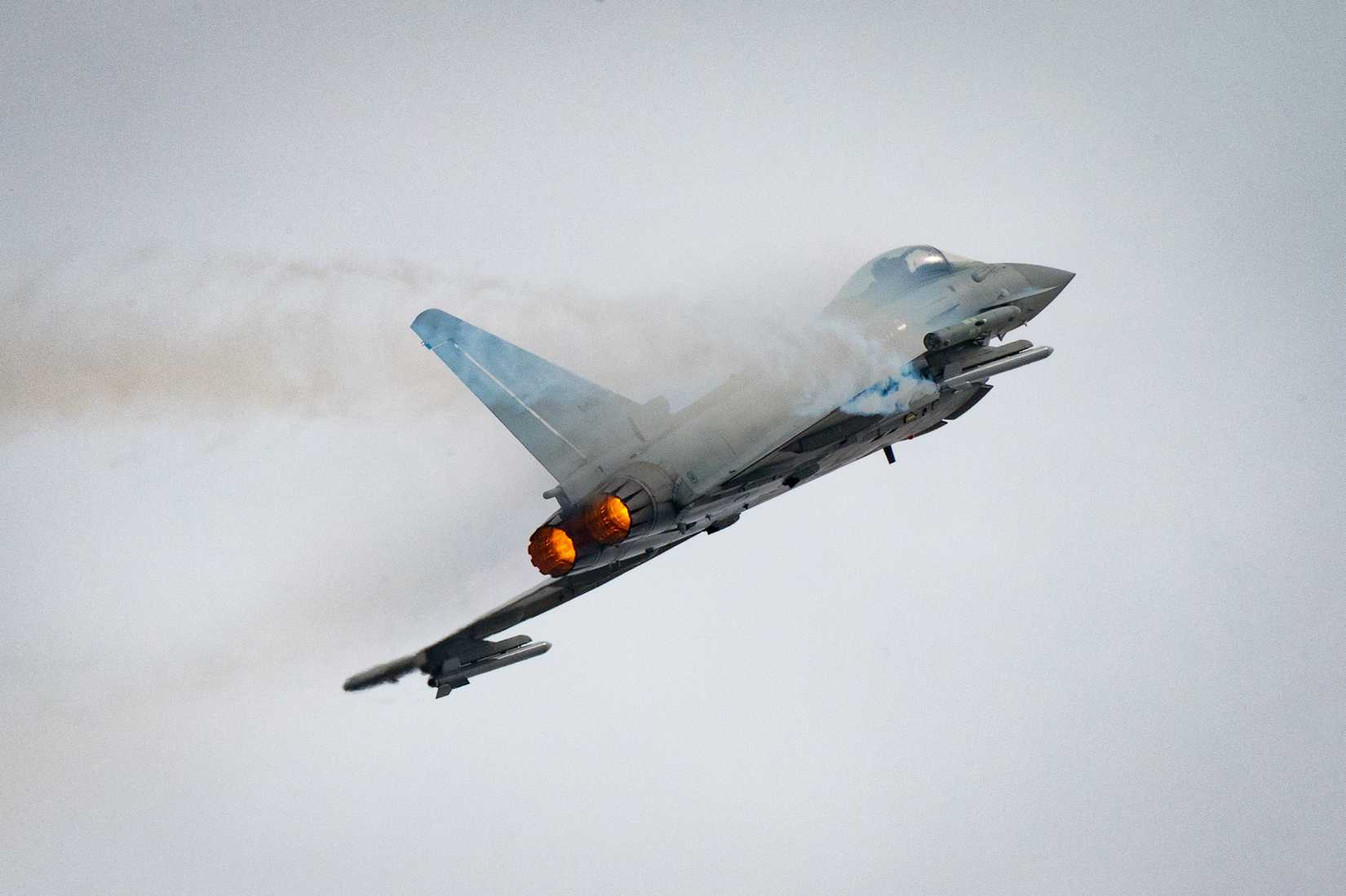 A Eurofighter Typhoon aircraft climbs with afterburners engaged during a flight demonstration at the Royal International Air Tattoo