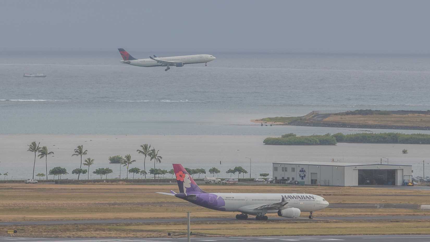 A Hawaiian Airlines A330 aircraft making a Kona departure with a Delta Air Lines jet in the background