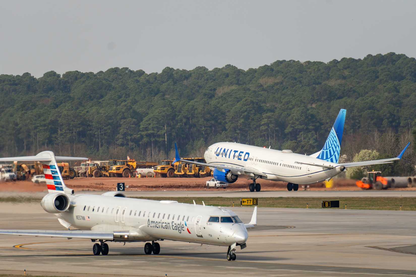 A United Airlines Boeing 737 passenger jet departs the runway as an American Eagle Bombardier CRJ-900 regional aircraft taxis at Raleigh-Durham International.