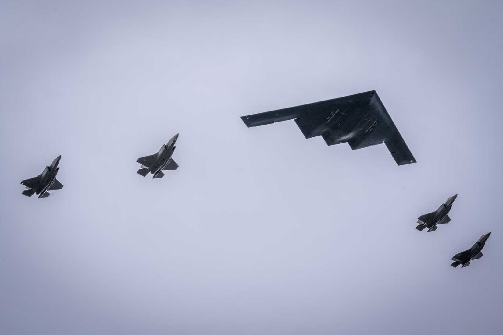 Air Force F-35 Lighting IIs and a B-2 Spirit fly over the flight line at Joint Base Elmendorf-Richardson, Alaska