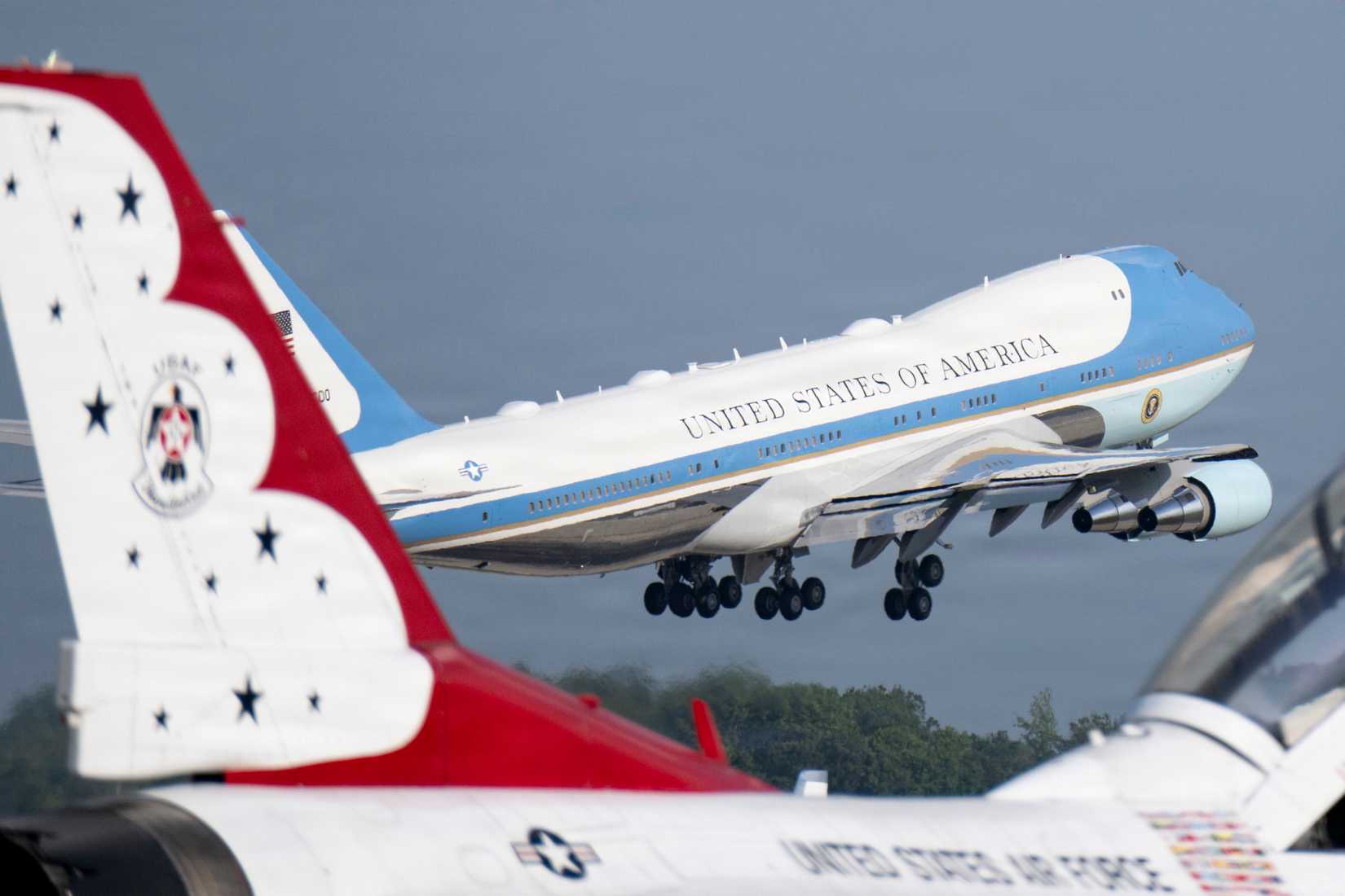 Air Force VC-25A assigned to the 89th Airlift Wing takes off in front of a F-16 Fighting Falcon