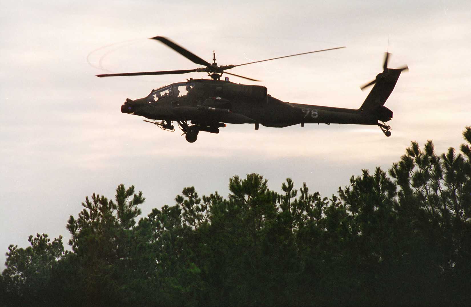 An AH-64 Apache helicopter patrols near the tree line during an exercise at at the Joint Readiness Training Center in 1996.