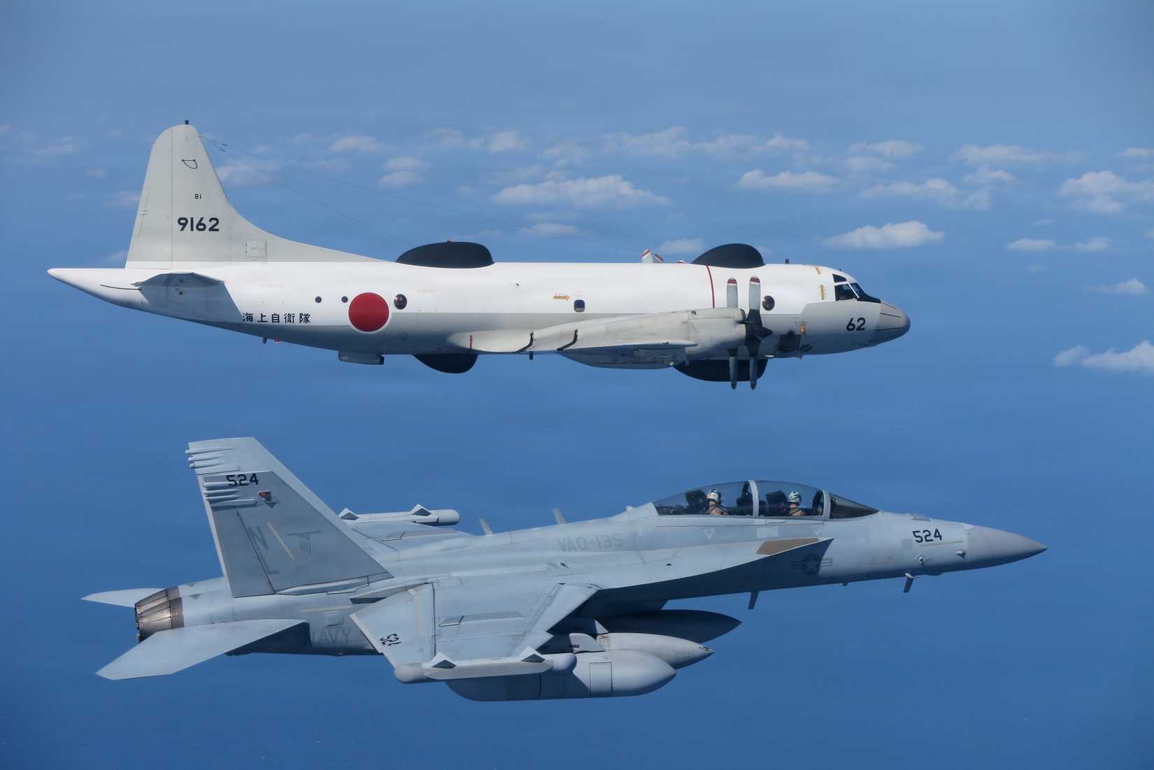 EA-18G Growler assigned to the “Black Ravens” of Electronic Attack Squadron (VAQ) 135, below, and an OP-3C Aries II assigned to Maritime Surveillance (VQ) 81, of the Japan Maritime Self-Defense Force