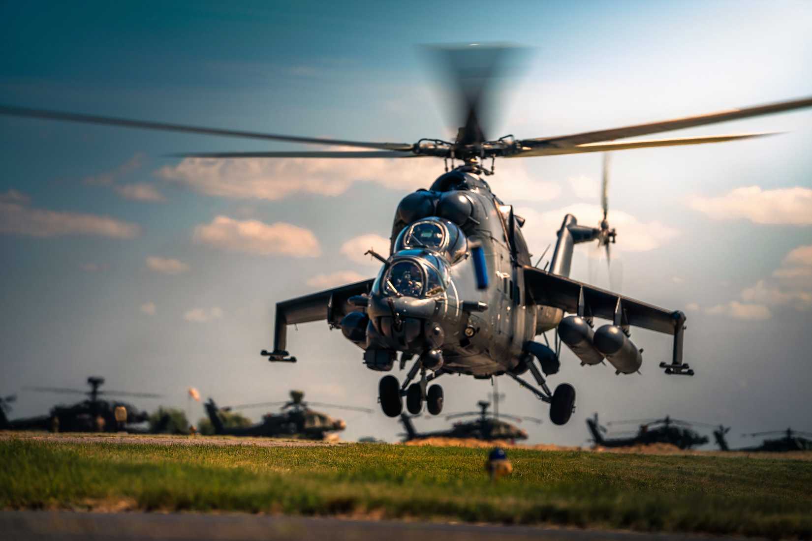 A Hungarian hind helicopter is seen hovering just above the runway of an airfield.