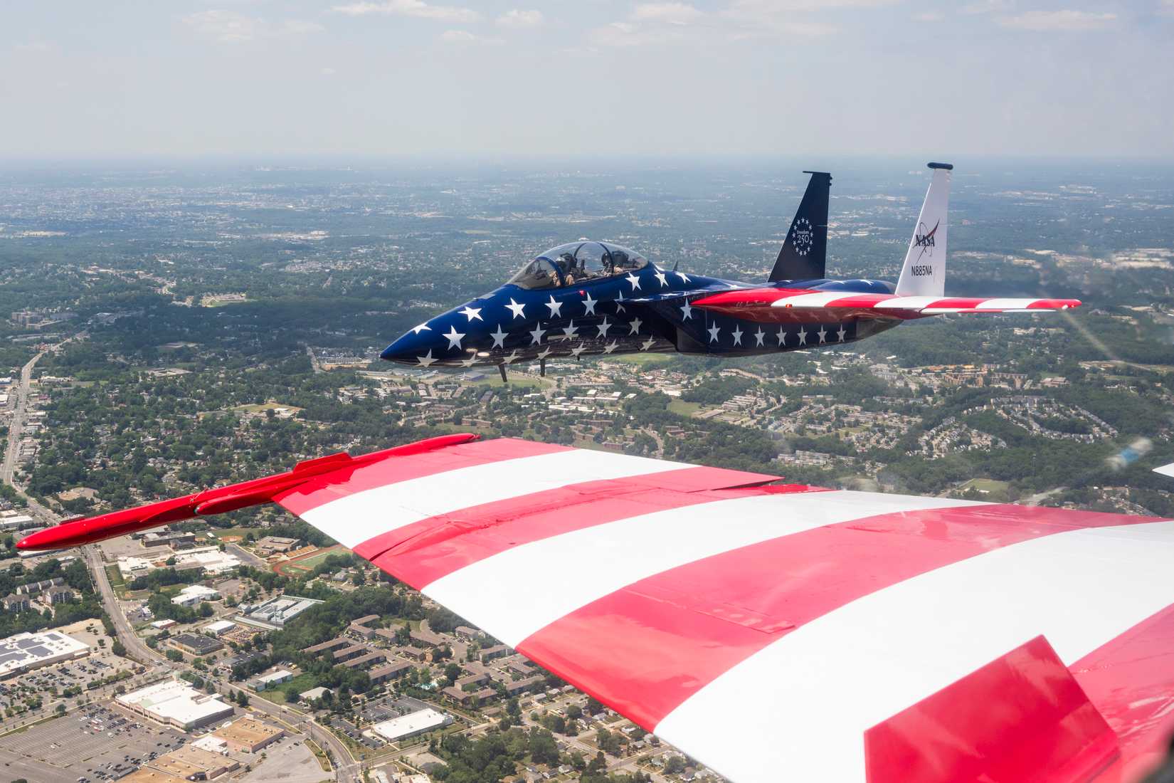 A NASA F-15 aircraft flies above Washington on Saturday, July 4, 2026, as part of a flyover to celebrate America’s 250th birthday. The wing of a NASA F-18 is seen in the foreground, as a NASA photographer captured this image from inside the cockpit.