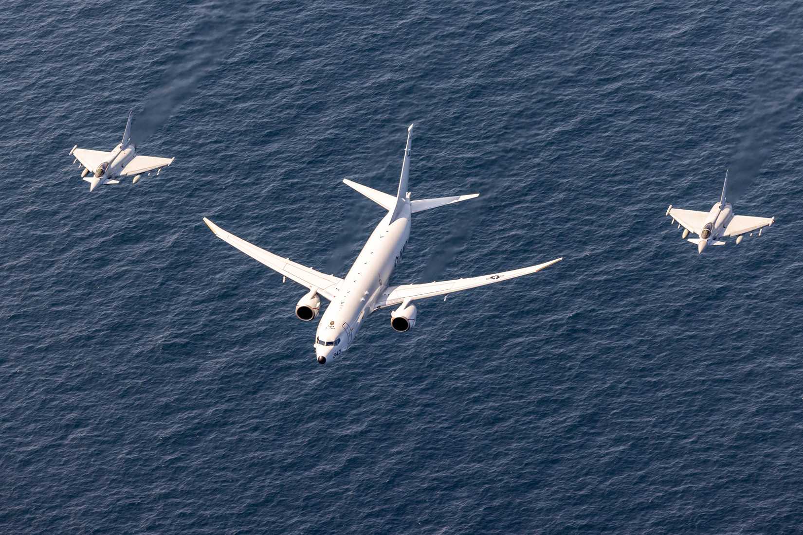 Navy P-8A Poseidon, center, and two Royal Air Force Eurofighter Typhoon fighter aircraft participate in an aerial formation