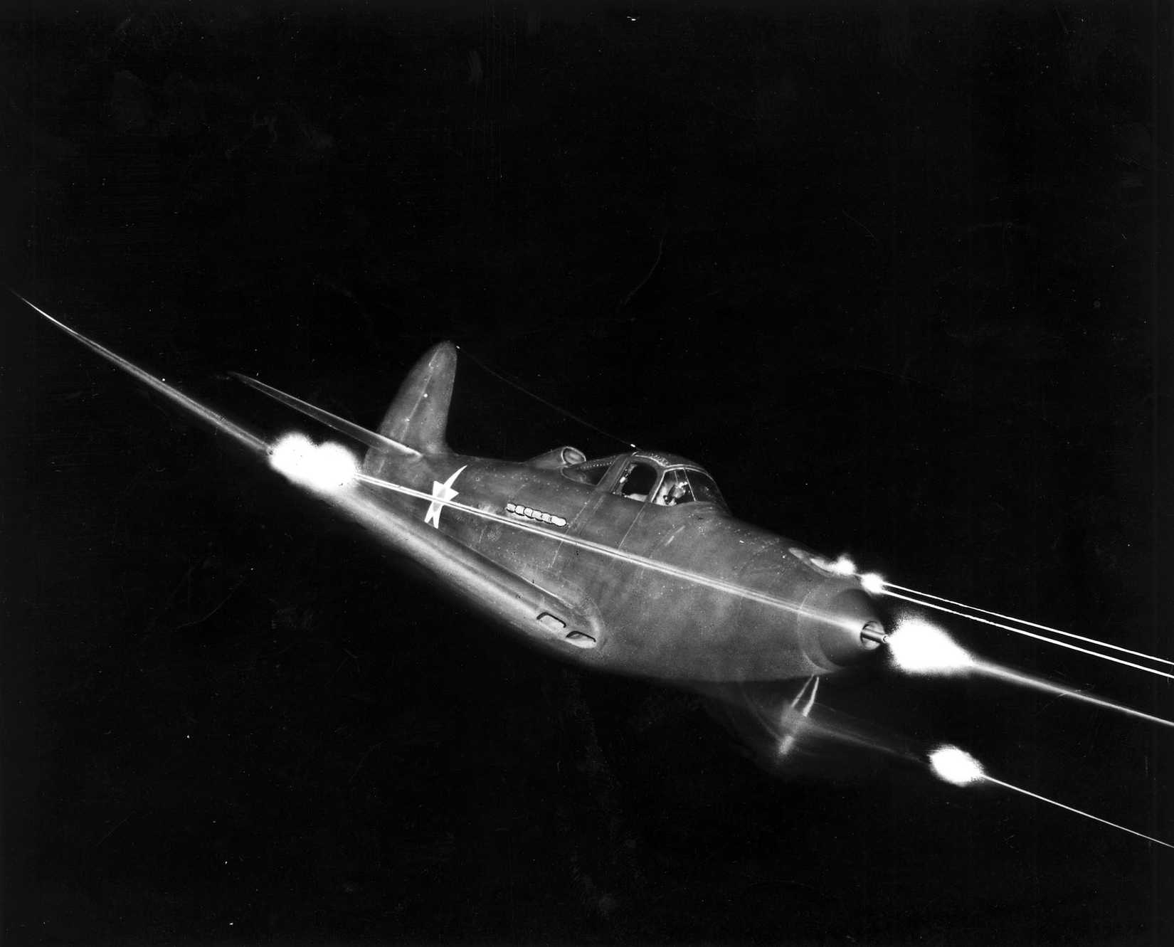 A photo of a P-39 Airacobra firing its weapons at night.