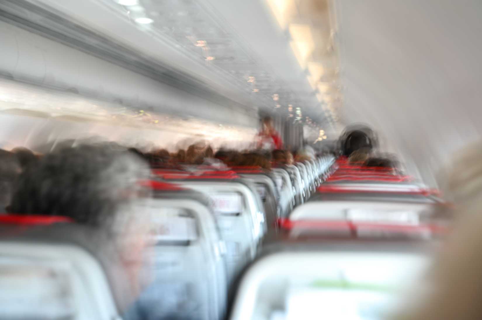Airplane turbulence. Passengers in cabin during turbulent flight. Blurred photo inside airplane.