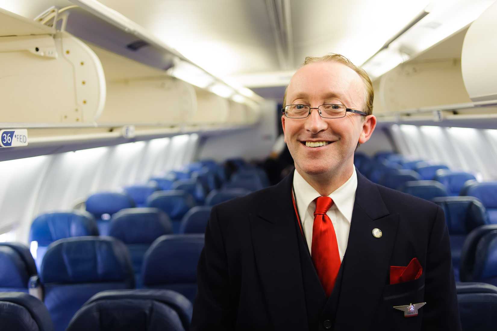 male flight attendant standing in aisle B757
