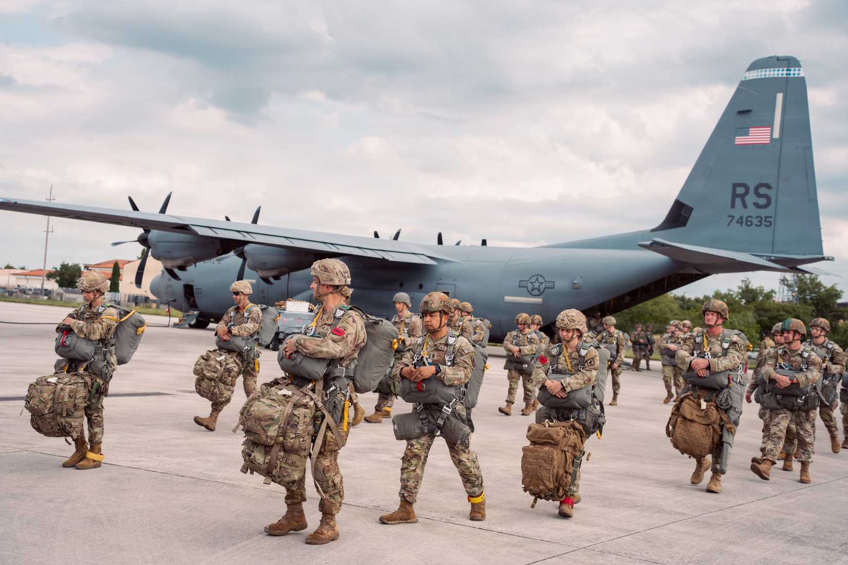 Soldiers assigned to the 173rd Mobile Brigade Combat Team walk across the airfield toward a U.S. Air Force C-130 at Aviano Air Base