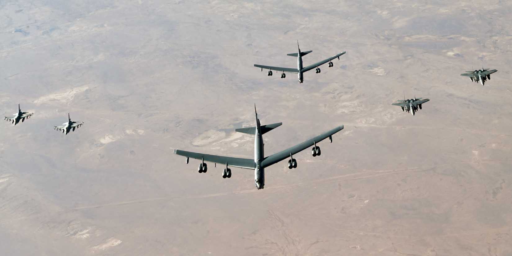 A photo showing B-52 bombers being escorted by F-15s and F-16s over a desert landscape.