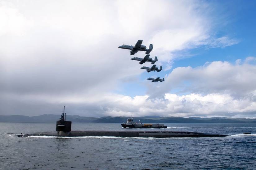 A photo of four A-10 Warthogs closely flying over the USS Nebraska, ballistic missile submarine in the Juan De Fuca Strait.