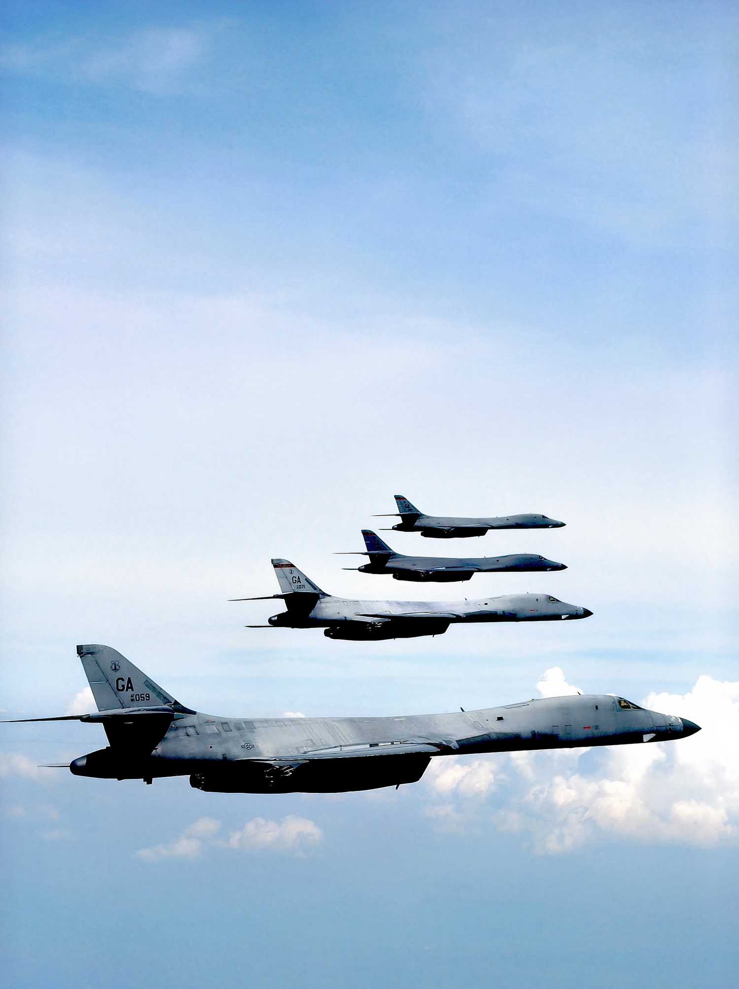 A photo of four B-1Bs flying in formation above the clouds.