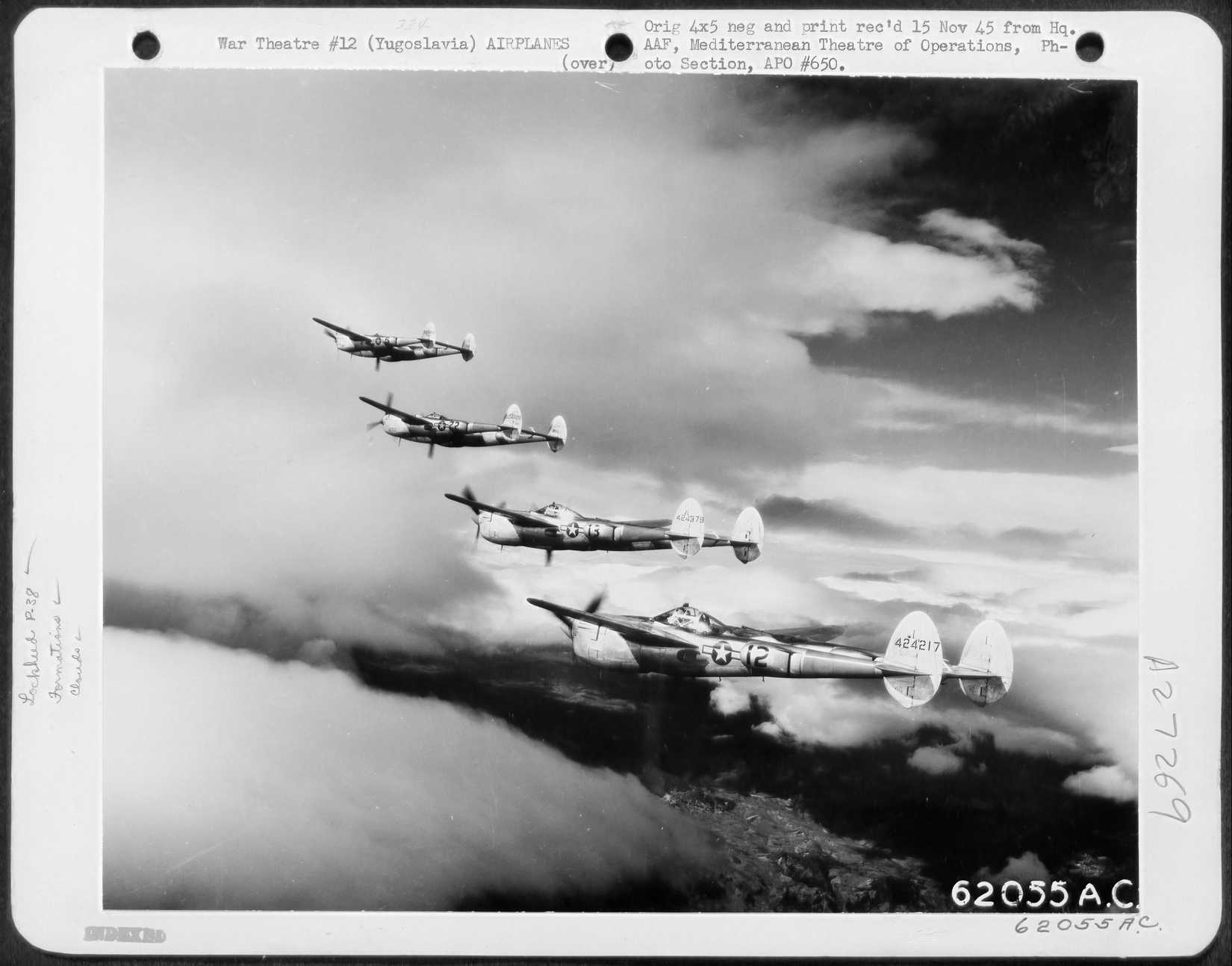 A formation of four P-38s flying high amongst the clouds. 