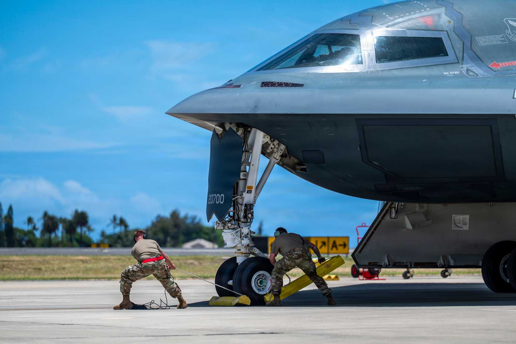 Air Force Airmen assigned to the 393rd Expeditionary Bomb Squadron pull the chocks for a B-2 Spirit stealth bomber